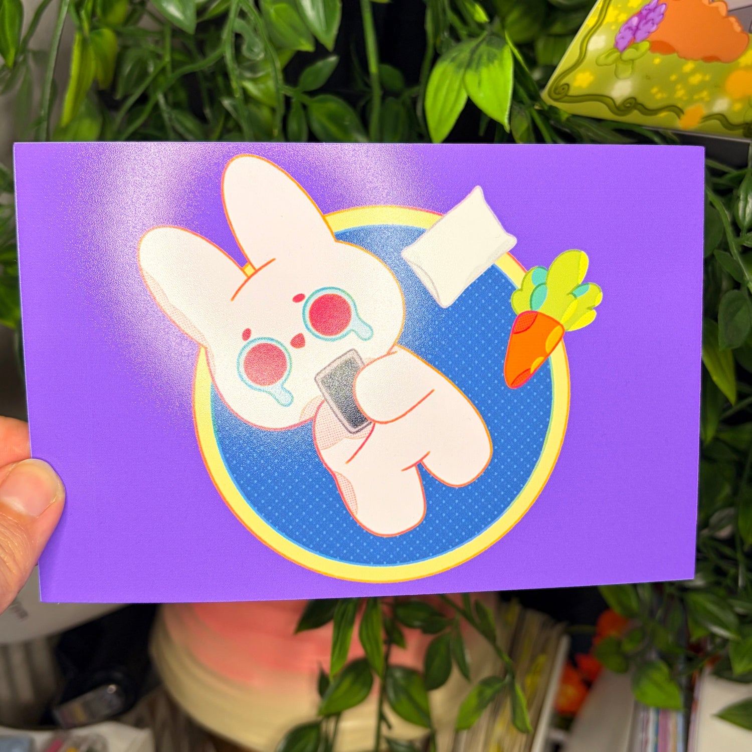 Card with cartoon character held in front of a plant