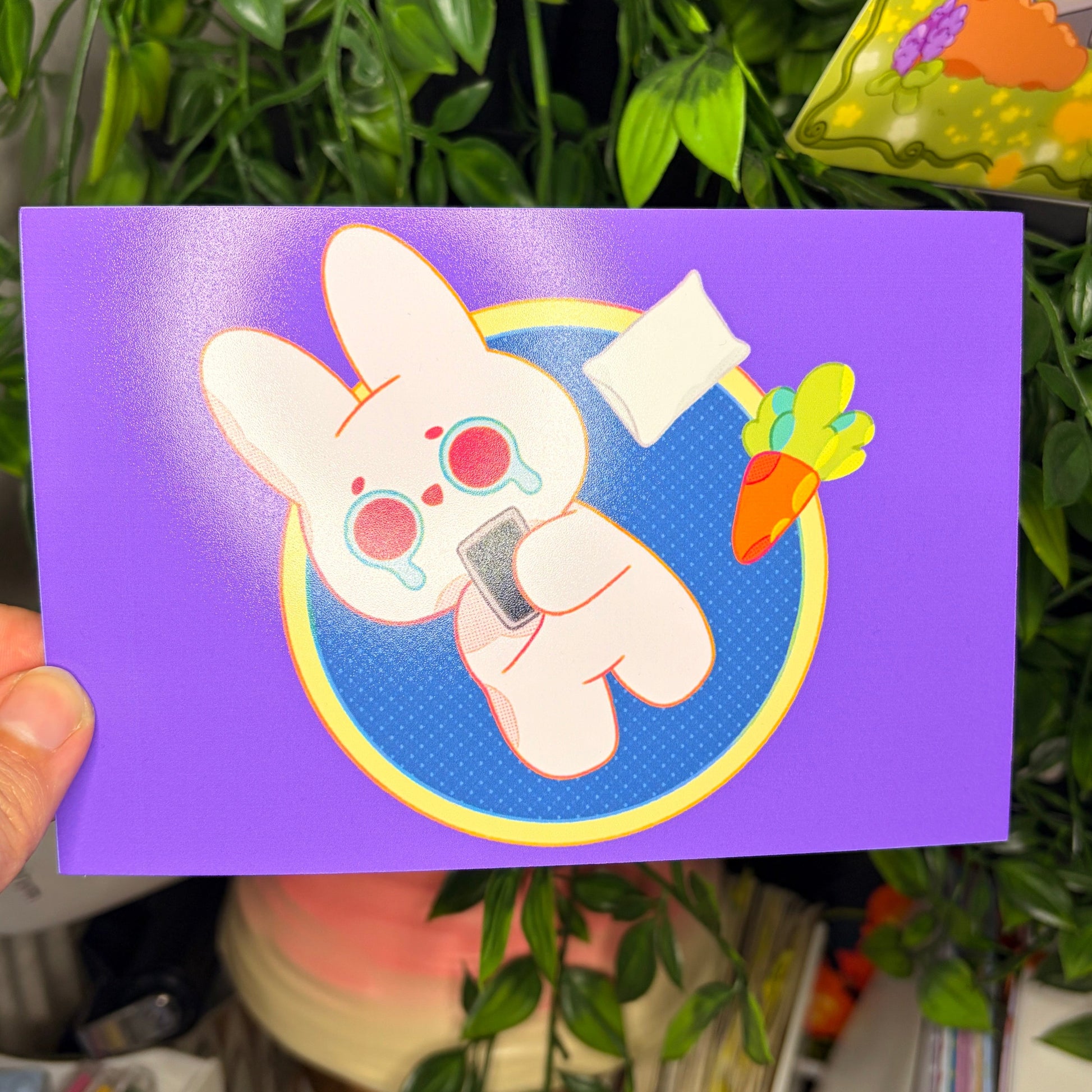 Card with cartoon character held in front of a plant