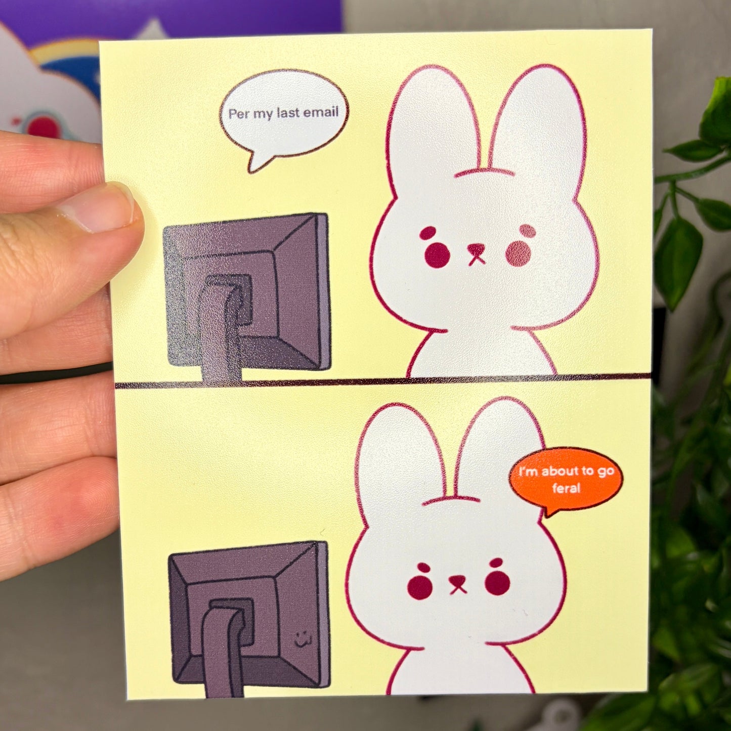 Cartoon rabbit character on a yellow card held by a hand with a blurred background